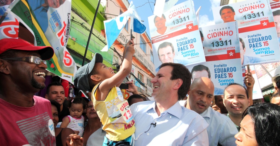 19.ago.2012 - O prefeito e candidato à reeleição, Eduardo Paes (PMDB), carrega uma criança durante caminhada, neste domingo, no Complexo do Alemão, zona norte da cidade