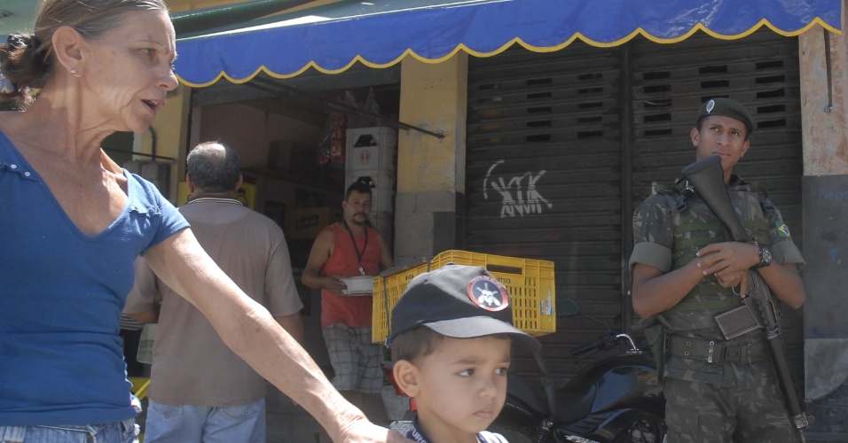 1.out.2012 - Moradores passam por soldados nas ruas do Rio de Janeiro. Na manhã desta segunda-feira (1) as Forças Armadas iniciaram uma série de operações em comunidades da capital para garantir a segurança dos eleitores no primeiro turno das eleições municipais, no próximo domingo (7)