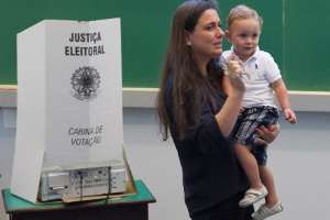 Eleitora acompanhada por criança ao registrar seu voto - Mister Shadow/Estadão Conteúdo