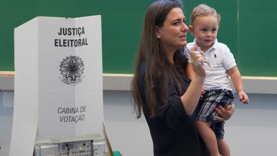 Eleitora acompanhada por criança ao registrar seu voto - Mister Shadow/Estadão Conteúdo